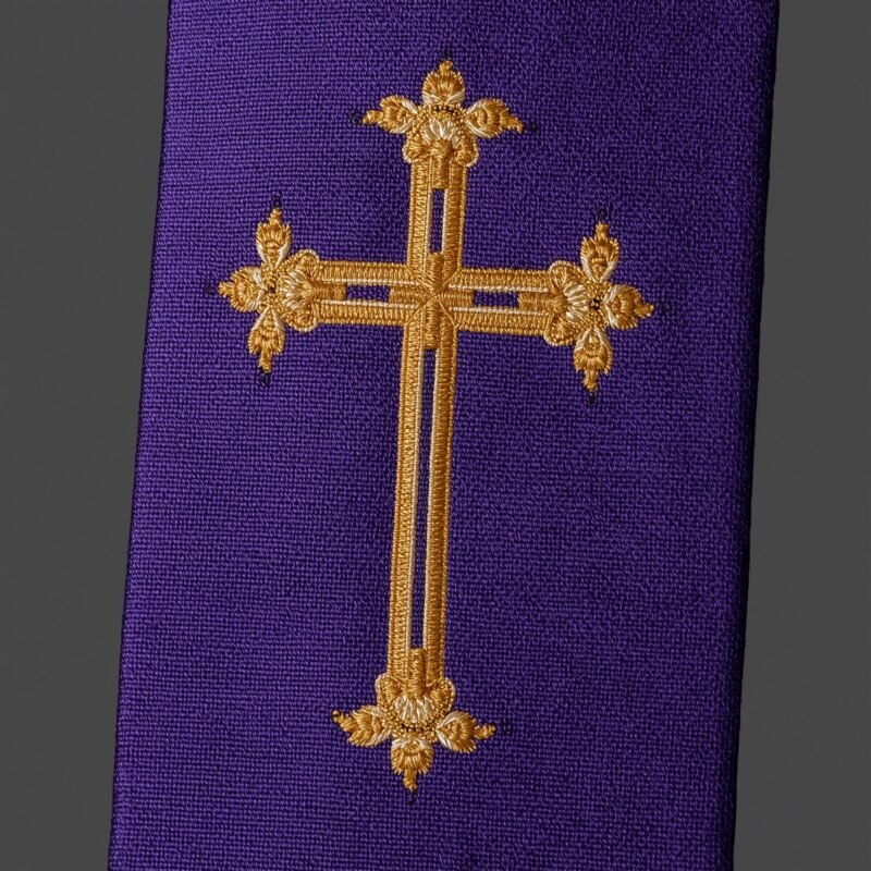 A close-up of a gold embroidered cross on a clergy stole.